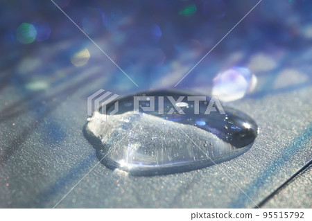 A drop of serum in tinsel in a Christmas theme in purple shades in dark tones. A drop of serum in tinsel in a Christmas theme in purple shades in dark tones. 95515792