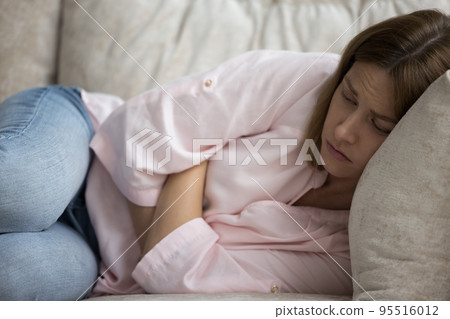 Woman feels unwell, looks unhealthy, lying on sofa at home Woman feels unwell, looks unhealthy, lying on sofa at home 95516012