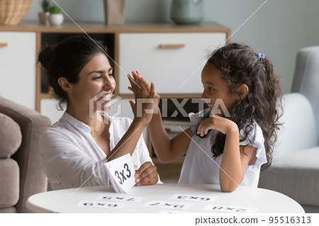 Indian mother checks daughters skills in multiplication 95516313