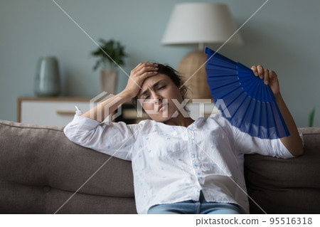 Indian woman suffers from heat inside cool herself waving fan 95516318