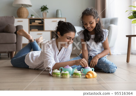 Mom and daughter play tea ceremony with cakes playthings indoors Mom and daughter play tea ceremony with cakes playthings indoors 95516364