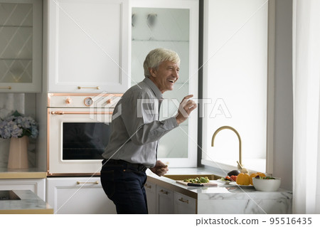 Carefree older man dancing in modern kitchen Carefree older man dancing in modern kitchen 95516435