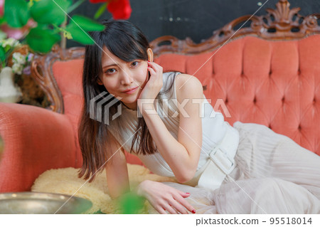 A Japanese woman lying on an orange sofa and a foliage plant A Japanese woman lying on an orange sofa and a foliage plant 95518014