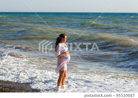 Portrait beautiful young pregnant woman, against blue sea on beach, thoughtful Portrait beautiful young pregnant woman, against blue sea on beach, thoughtful 95520087