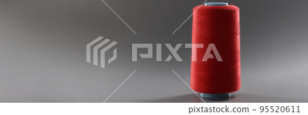 Red colour thread spool on grey background, yarn for sewing, bright thread for dressmaking Red colour thread spool on grey background, yarn for sewing, bright thread for dressmaking 95520611