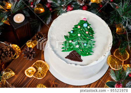 Christmas cake made of chocolate base with cream, decorated with a chocolate Christmas tree against the backdrop of Christmas decor 95521978