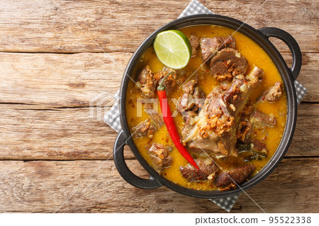Indonesian food gulai kambing goat curry spicy stew closeup on the wooden table. Horizontal top view 95522338