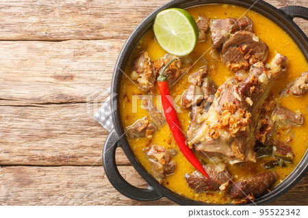 Gulai Kambing traditional Javanese mutton curry stew closeup on the wooden table. Horizontal top view 95522342