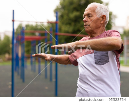 Elderly man doing fitness exercises outdoors Elderly man doing fitness exercises outdoors 95522734