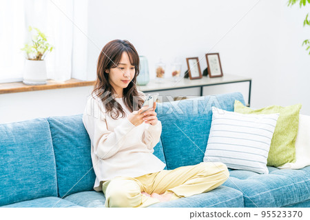 Young woman looking at her smartphone in the living room 95523370