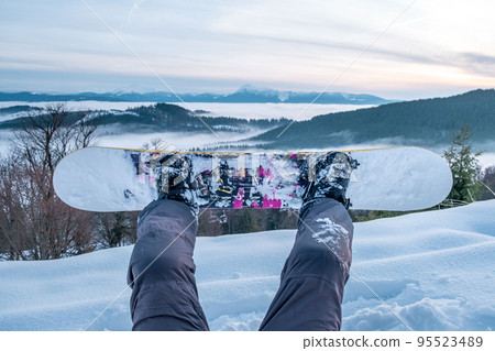 snowboarder enjoying the view of sunset above the mountains 95523489
