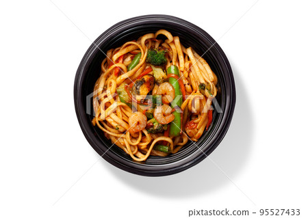 Spicy udon noodles with stir fried shrimps, mussels, calamari and vegetables in bowl 95527433