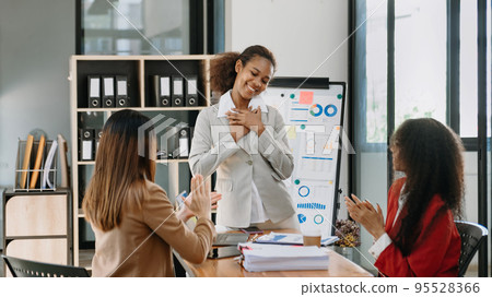 Mid age Asian business woman ceo executive manager showing to colleagues team income revenue data figures planning on big screen in office. 95528366