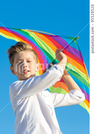 A boy of 8-9 years old happily launches a kite into the sky 95528528