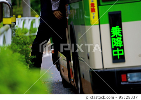 Passengers getting off the metropolitan bus at the bus stop (male office worker) 95529337