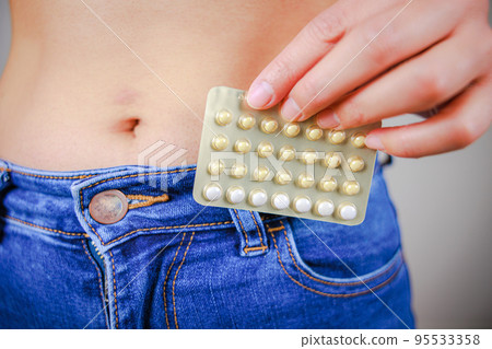 Female hand holding oral contraceptive (low dose pill) 95533358
