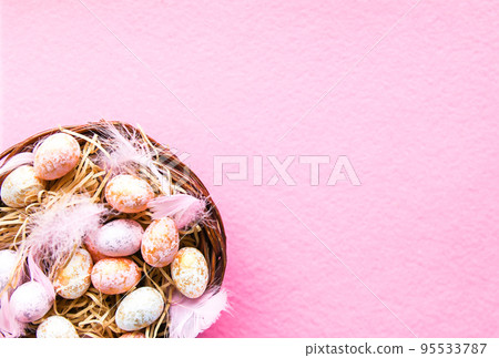Easter composition with traditional decor. Small decorative colorful eggs and soft feathers on pink background. 95533787