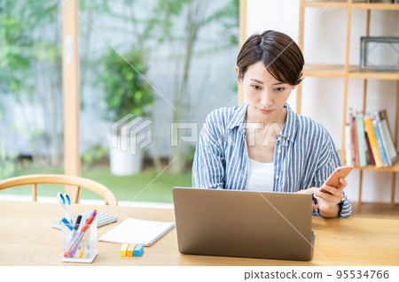 A middle-aged woman who teleworks in the living room. A middle-aged woman who teleworks in the living room. 95534766