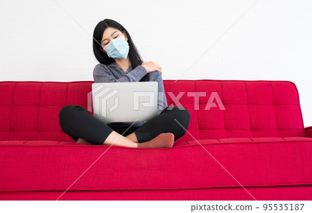 Tired woman wearing a face mask,  pain in neck tensed muscles fatigued from computer work, suffering of office syndrome after long hours work on computer. Office syndrome and Health care concept. 95535187