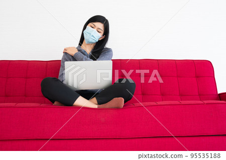 Tired woman wearing a face mask, pain in neck tensed muscles fatigued from computer work, suffering of office syndrome after long hours work on computer. Office syndrome and Health care concept. Tired woman wearing a face mask, pain in neck tensed muscles fatigued from computer work, suffering of office syndrome after long hours work on computer. Office syndrome and Health care concept. 95535188