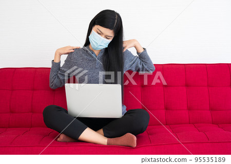 Tired woman wearing a face mask,  pain in neck tensed muscles fatigued from computer work, suffering of office syndrome after long hours work on computer. Office syndrome and Health care concept. 95535189