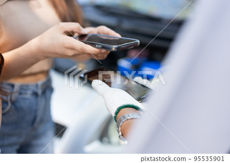 Asian women get contact numbers from Asian male auto mechanics after fixing the car engine problem and QR code scan to pay for fixing vehicle service. Car repair, and maintenance concept. Asian women get contact numbers from Asian male auto mechanics after fixing the car engine problem and QR code scan to pay for fixing vehicle service. Car repair, and maintenance concept. 95535901