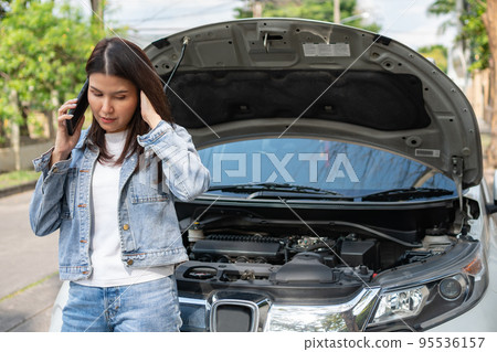 Angry Asian woman and using mobile phone calling for assistance after a car breakdown on street. Concept of vehicle engine problem or accident and emergency help from Professional mechanic Angry Asian woman and using mobile phone calling for assistance after a car breakdown on street. Concept of vehicle engine problem or accident and emergency help from Professional mechanic 95536157