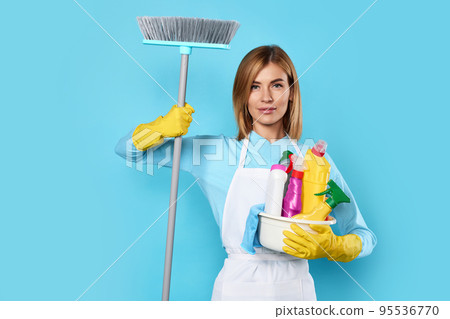 woman in gloves holding bucket of detergents and broom 95536770