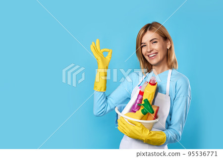 woman in gloves holding bucket of detergents and showing Ok woman in gloves holding bucket of detergents and showing Ok 95536771