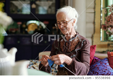 Senior smiling woman in casualwear knitting new clothes for her family 95536998