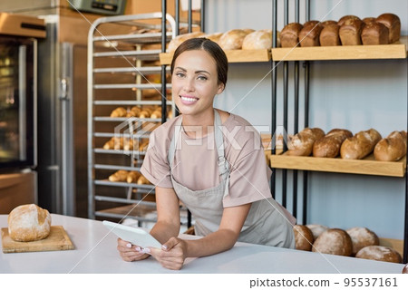 Ai generated face of young pretty worker or owner of bakery with tablet 95537161