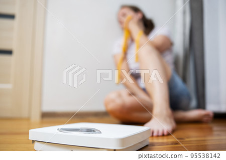 White scale and depression, upset and sad woman with measuring tape 95538142