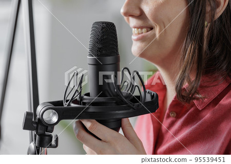 woman in a home office records podcast audio content with a microphone and headphones and a labrador dog 95539451