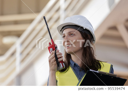 female engineer with a walkie-talkie at the construction site gives instructions. European successful female technologist female engineer with a walkie-talkie at the construction site gives instructions. European successful female technologist 95539474