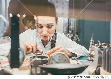 Woman watchmaker working diligently on repairing a watch Woman watchmaker working diligently on repairing a watch 95540215