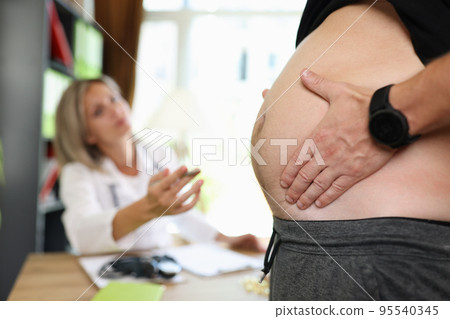 Man touching and showing fat belly to doctor nutritionist Man touching and showing fat belly to doctor nutritionist 95540345