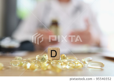 Transparent yellow capsules and wooden cube with letter d Transparent yellow capsules and wooden cube with letter d 95540352