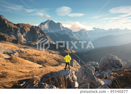Man on the stone and beautiful high rocks at colorful sunset Man on the stone and beautiful high rocks at colorful sunset 95540877