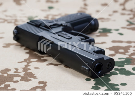 modern hand gun on camouflaged uniform 95541100