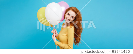 Celebrating Concept - Close up Portrait happy young beautiful attractive redhair girl smiling with colorful party balloon. Blue Pastel Background. 95541430
