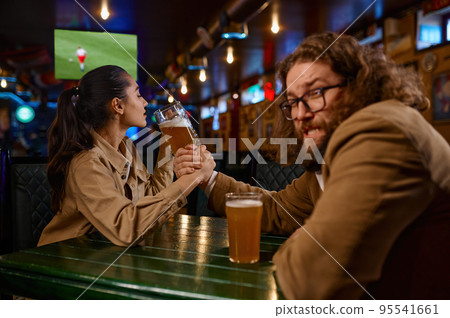 Arm wrestling challenge between man and woman at pub 95541661