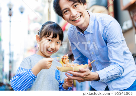 在大阪道頓堀觀光時吃章魚燒的父母和孩子 95541805
