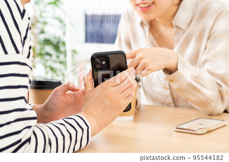 Two young women talking while looking at a smartphone Two young women talking while looking at a smartphone 95544182
