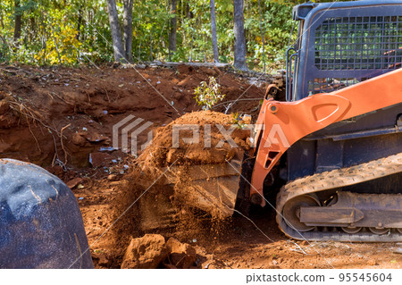 Small tractor used to move soil for landscaping on construction site. 95545604