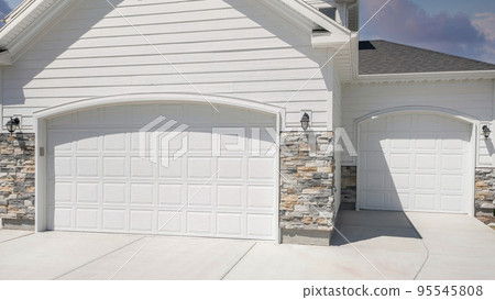 Panorama Puffy clouds at sunset Three car garage exterior with two white garage doors with arche 95545808