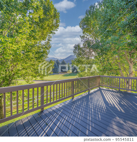 Square White puffy clouds Wooden deck of a house with a beautiful view of green fields and 95545811