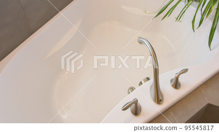 Panorama Corner bathtub with stainless faucet and potted plant on deck Panorama Corner bathtub with stainless faucet and potted plant on deck 95545817