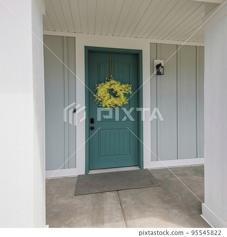 Square Front porch of a house with blue green front door and yellow wreath 95545822