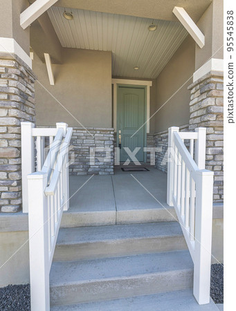 Vertical Facade of a house with white railings at the entrance near the white garage door Vertical Facade of a house with white railings at the entrance near the white garage door 95545838