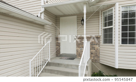 Panorama Entrance of a house with white vinyl wood siding and bay windows 95545847